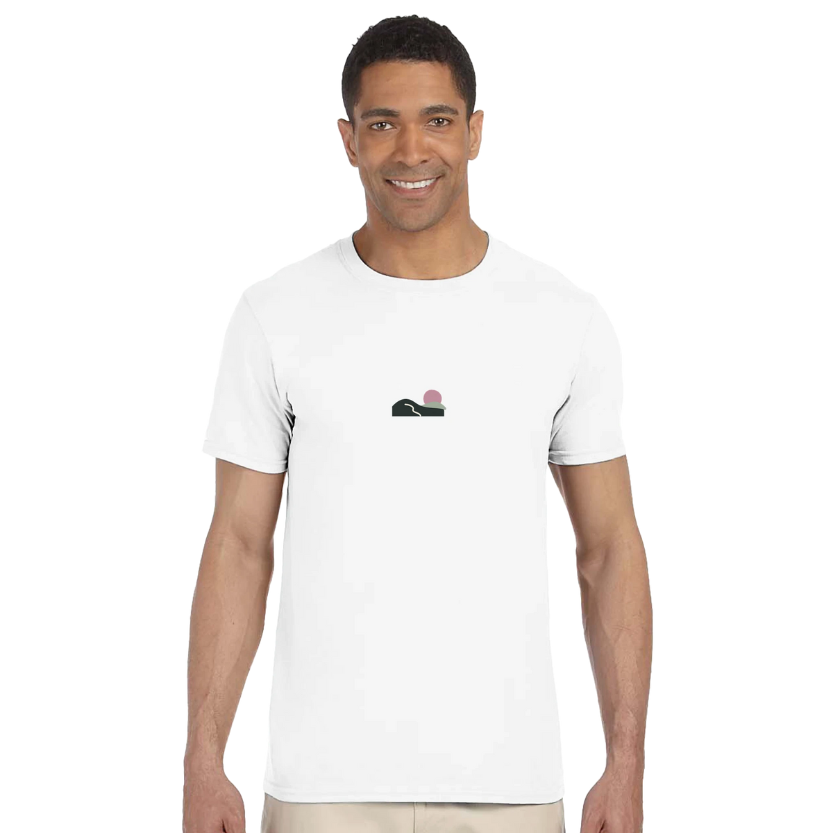 Model wearing the white Slow Sunday T-shirt, with a small green-hills illustration, winding cream path and dusty-pink sun on the front.